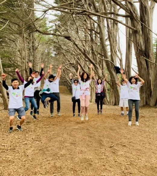 A group of children and adults jumping for joy on a forest trail